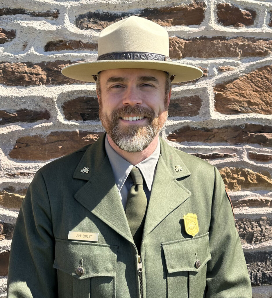 National parks superintendent Jim Bailey stands in front of a stone wall
