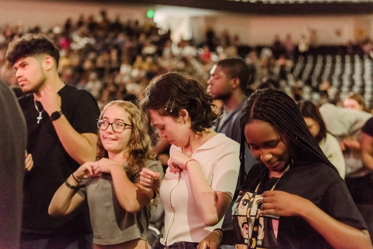 Three students look down concentrating as they pin a UMBC pin on themselves