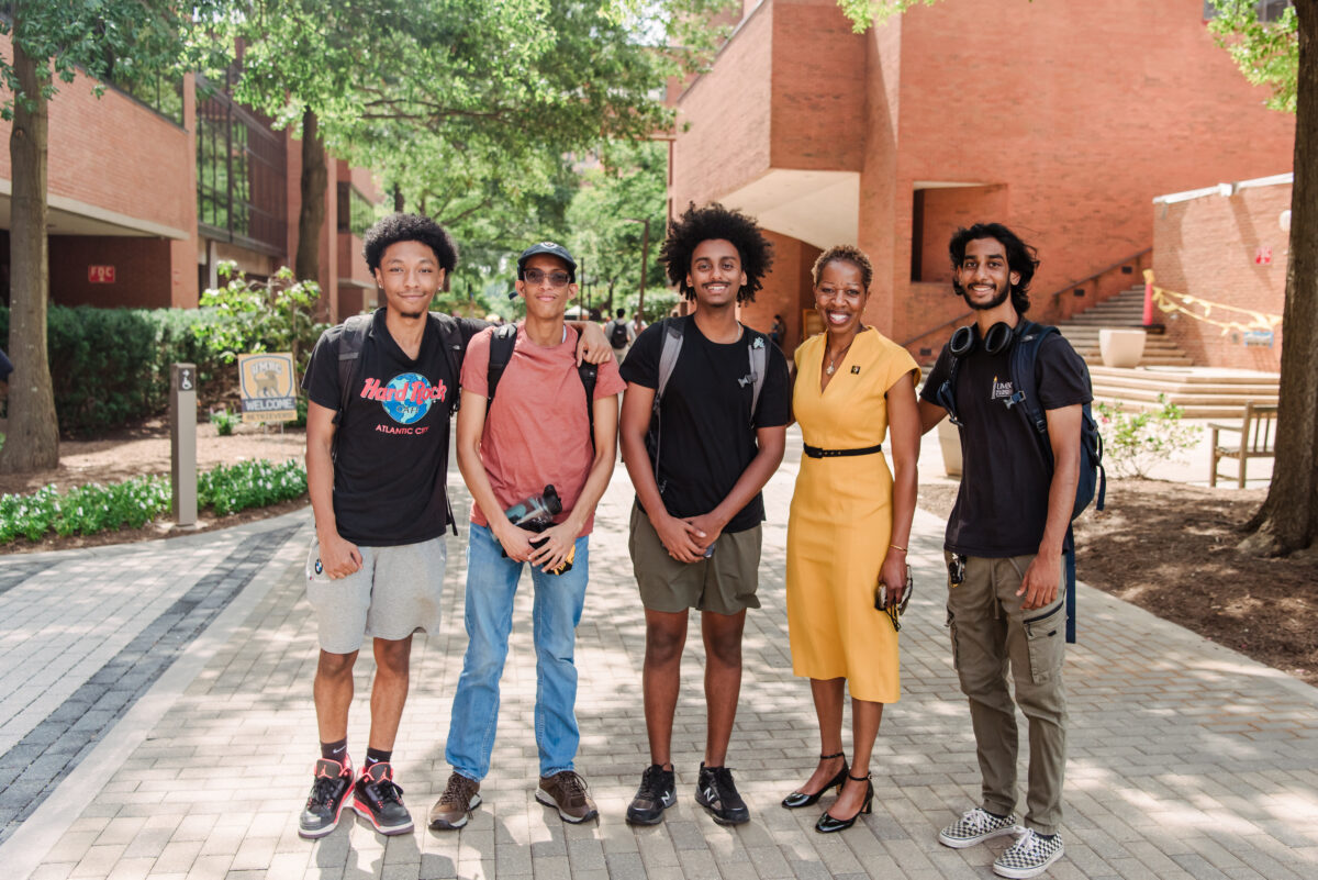 UMBC's president stands with four students smiling outside on the first day of classes