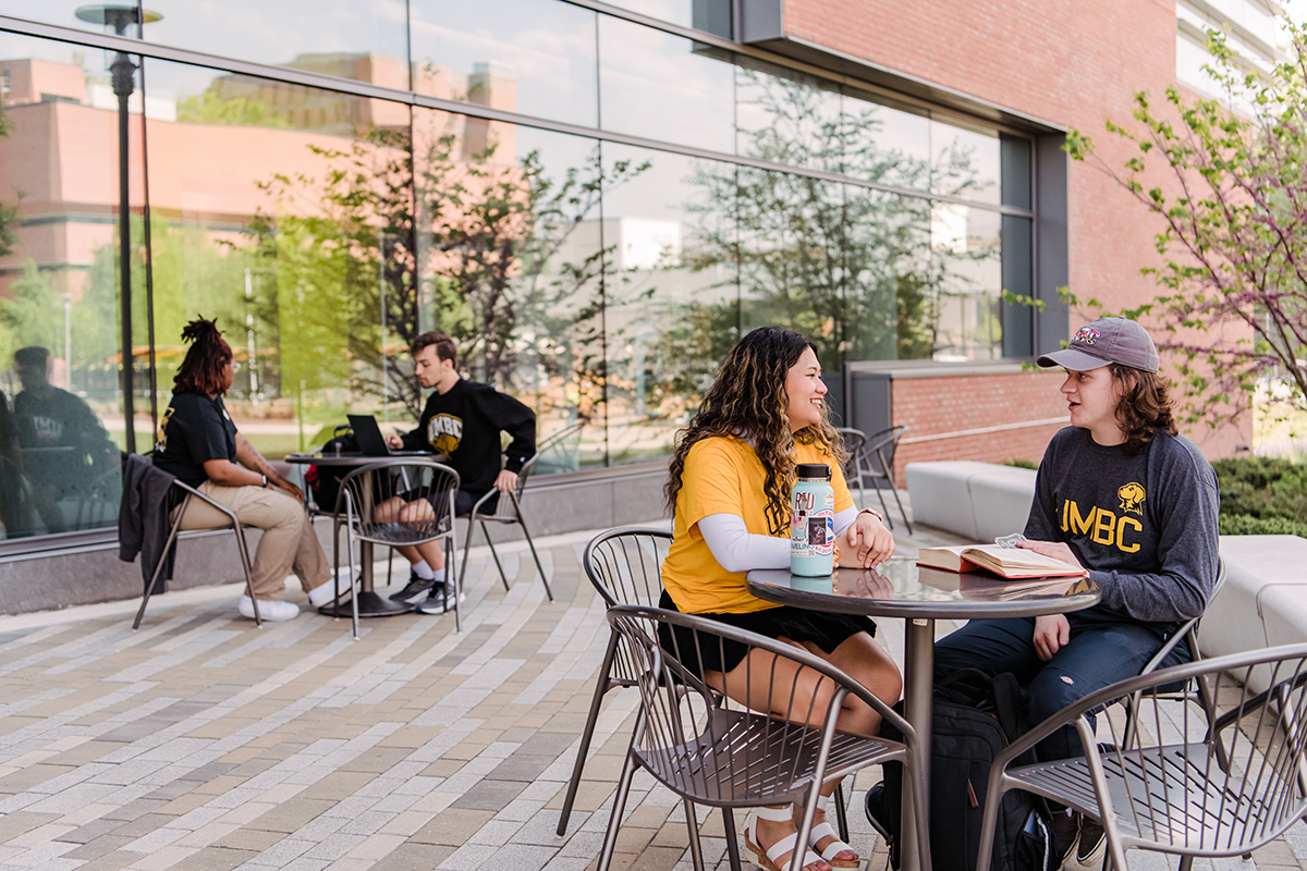 Two pairs of students sitting at tables outside