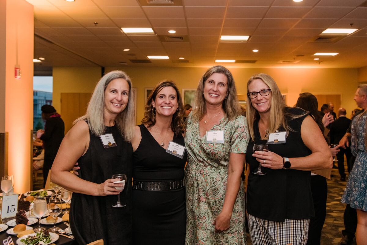 A group of four women pose together at the reception following a formal event honoring retrievers at UMBC.