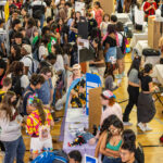 Students talk to each other about clubs in a large room.