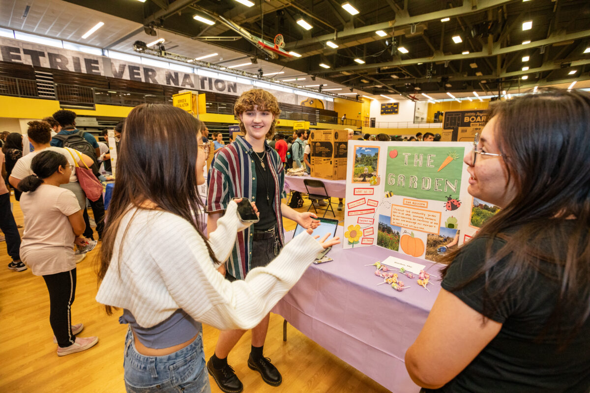 Two students share information with another student about their club, The Garden.