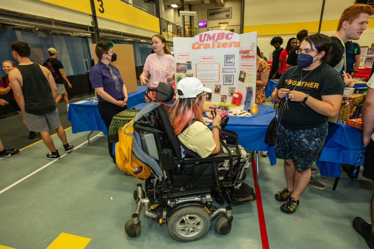 A student in a wheelchair talks with another student about crafting.