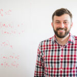 portrait of man standing in front of whiteboard with equations