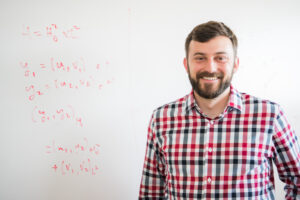 portrait of man standing in front of whiteboard with equations
