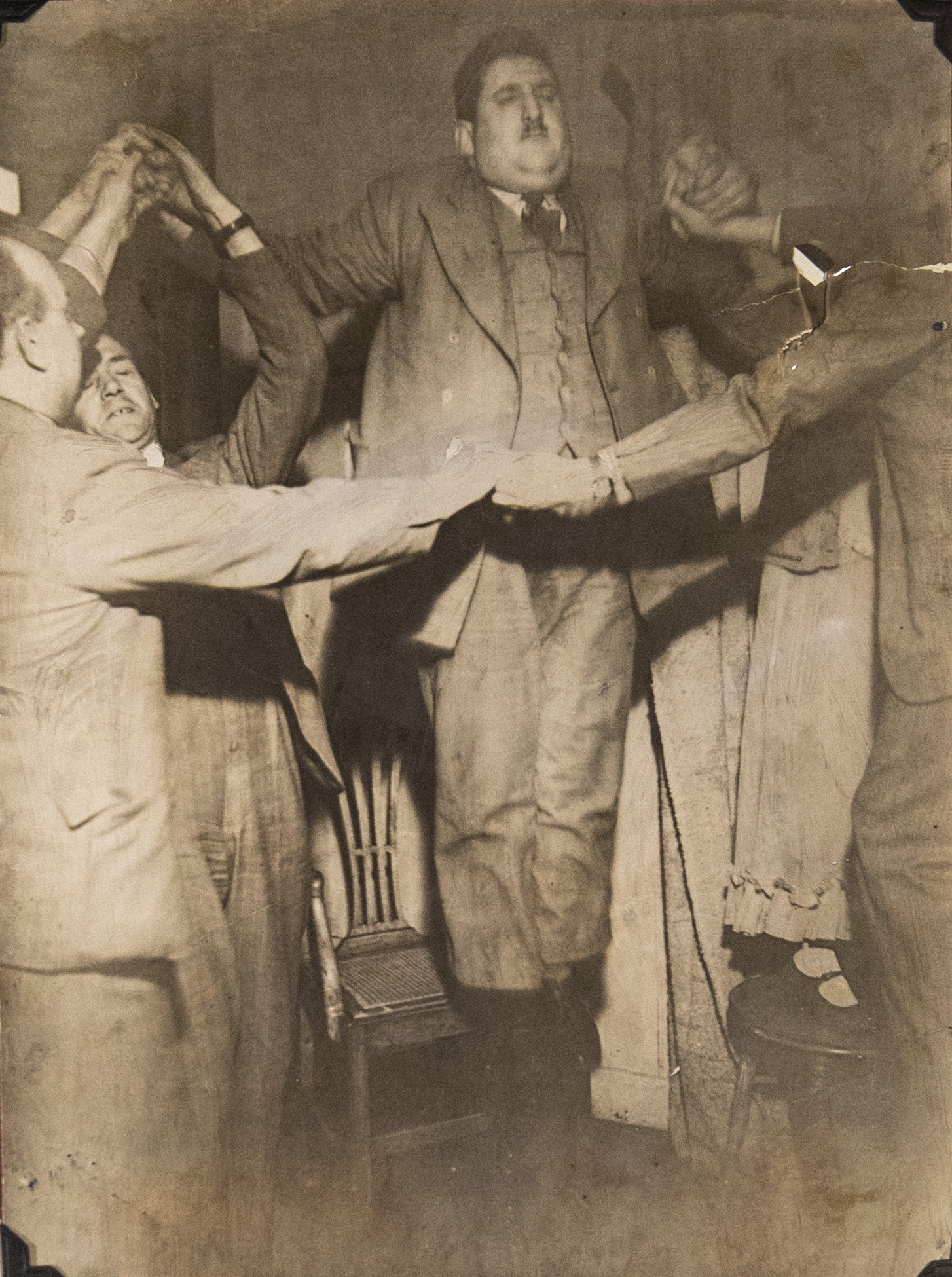 In an old sepia-toned photograph of a seance, a man appears to levitate
