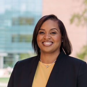 Portrait of Tanyka Barber, wearing a gold shirt and black blazer to represent UMBC.