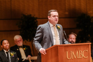 a man stands behind a lectern that says UMBC