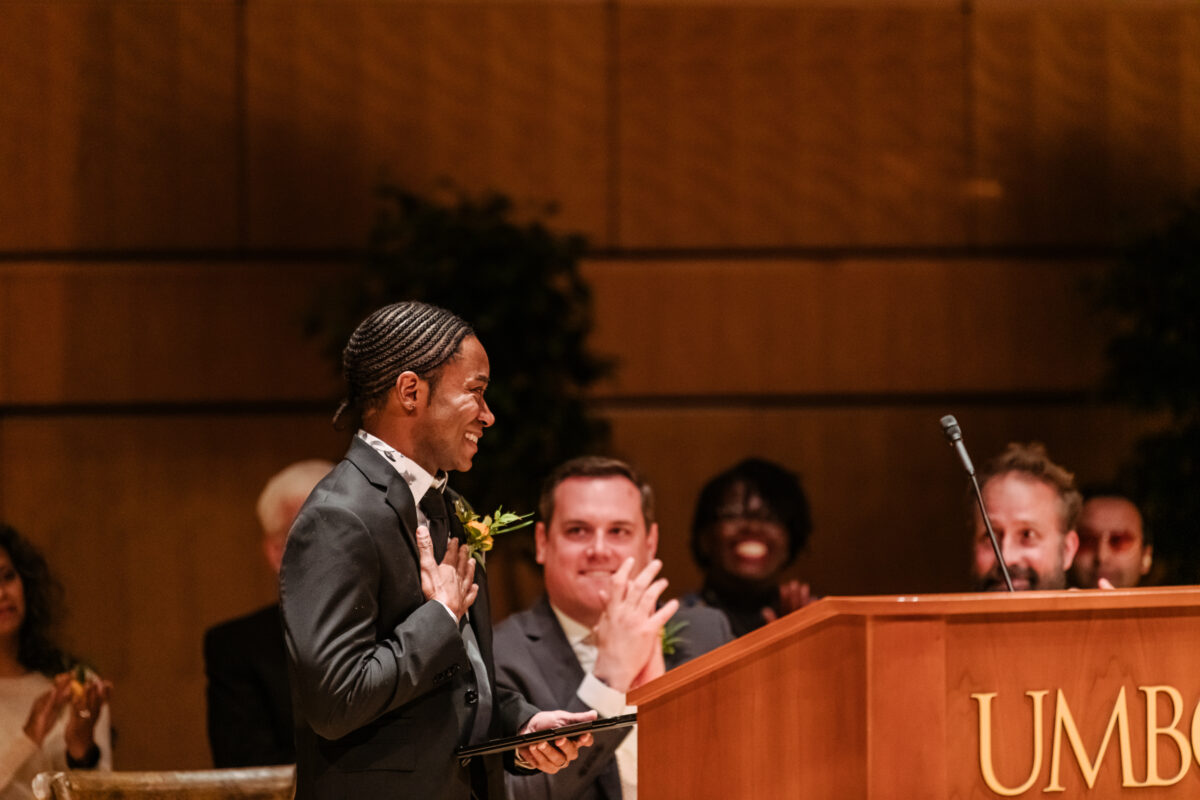 a man stands at a lectern with his hand on his heart