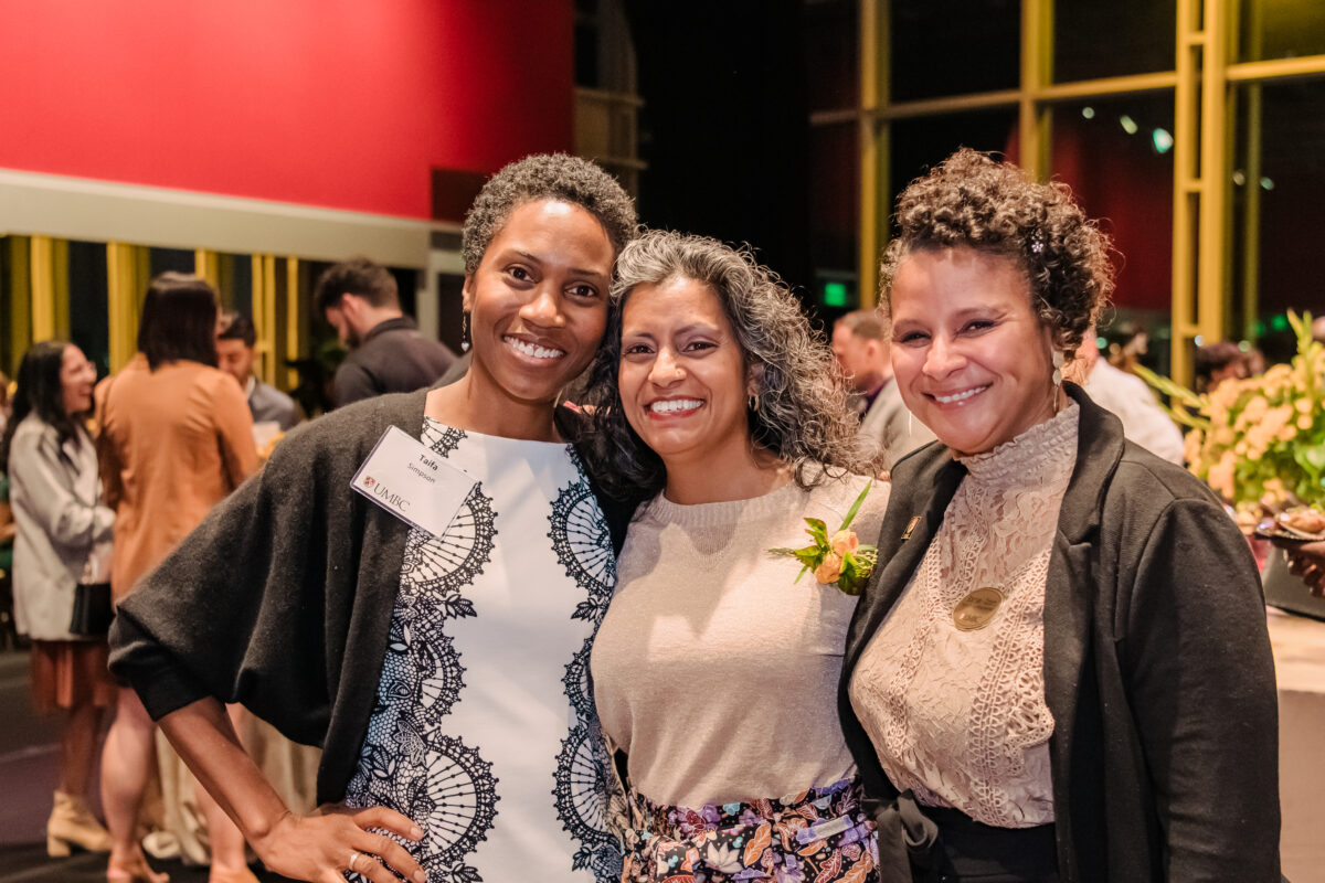 three women pose together at a fancy event