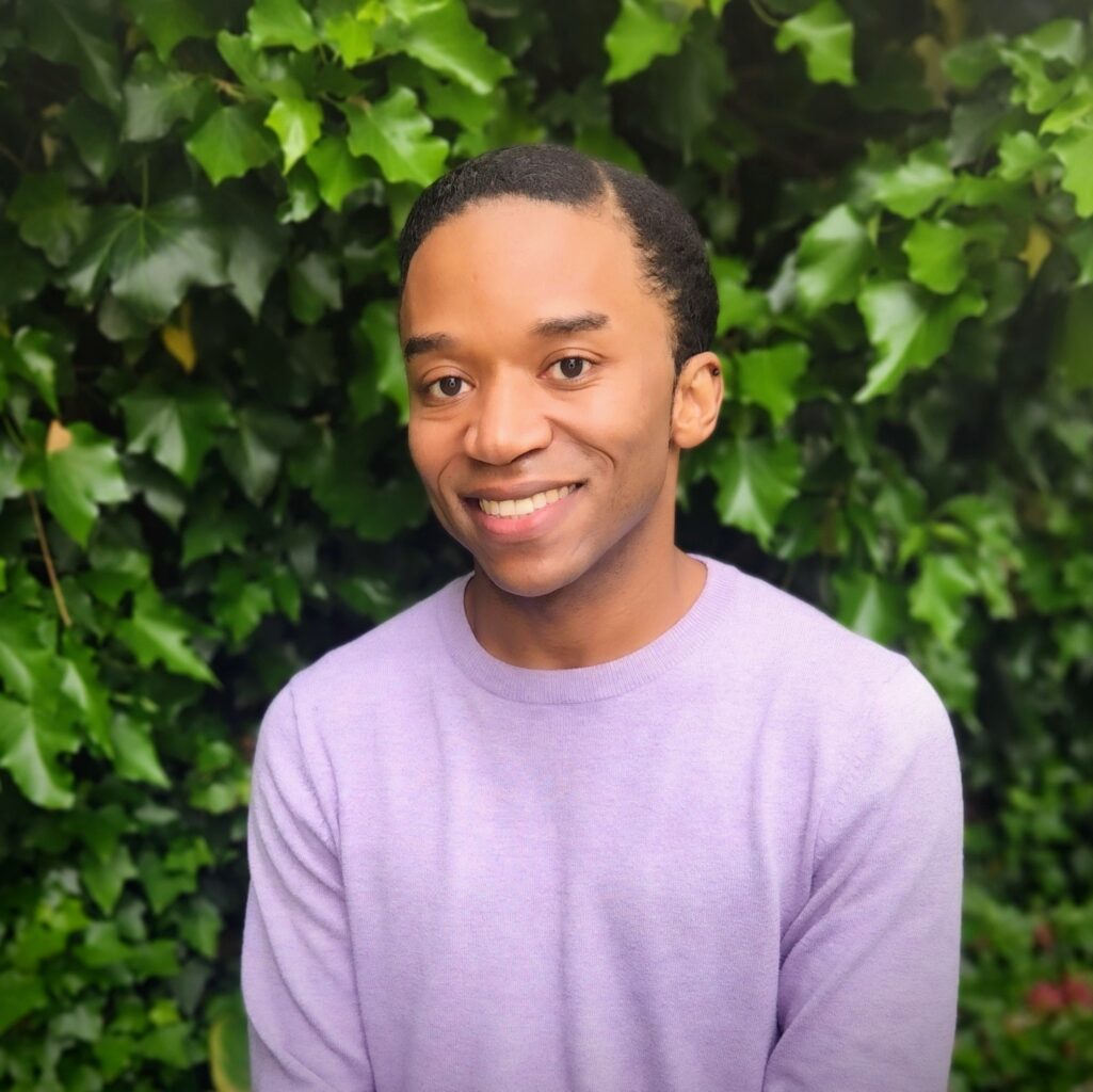 Headshot of James Dorsey in a lavender sweater in front of greenery