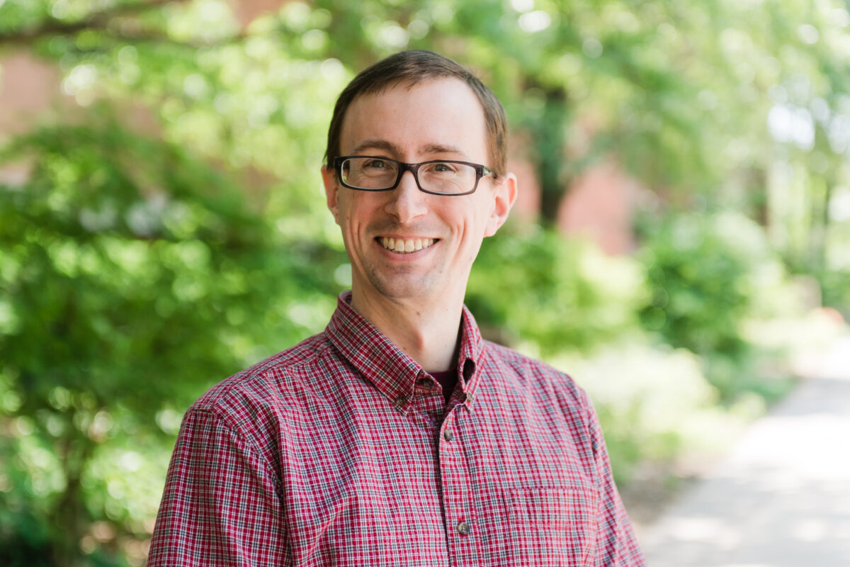 portrait of man in checked button-down and glasses outdoors