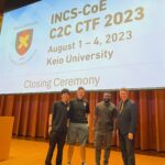 Four men standing on stage in front of a screen that says "INCS-COE C2C CTF 2023, August 1-4, 2023, Keio University, closing ceremony"