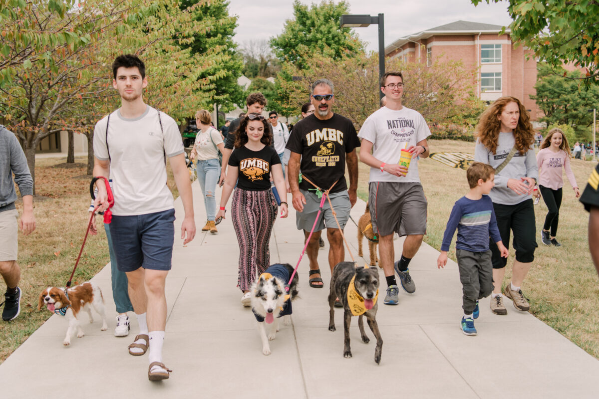 a group of people parade their dogs across campus