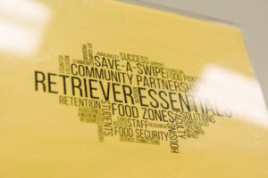 Printed text on yellow background as a word cloud, including words "Retriever Essentials. Community partnerships. Save-a-swipe"