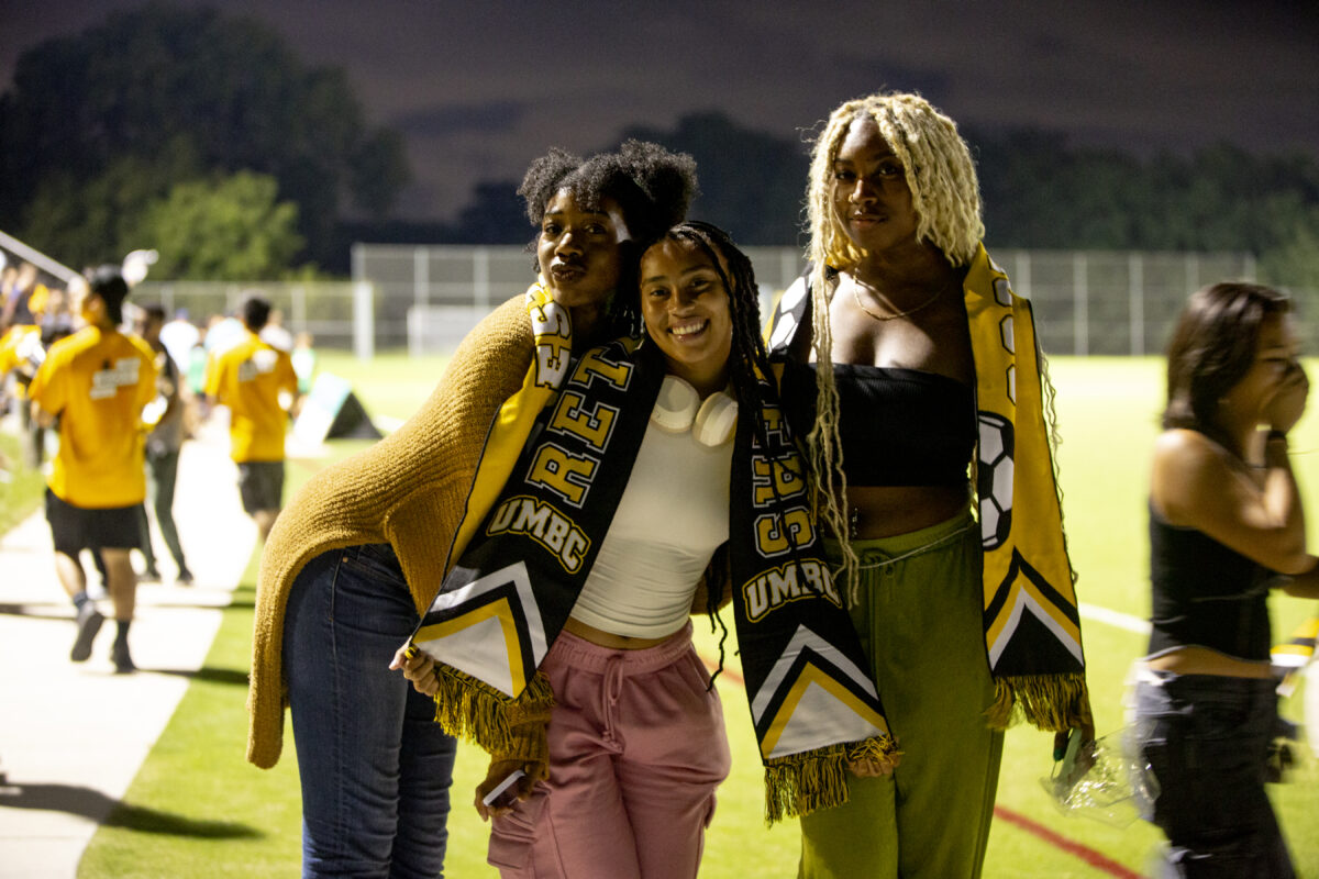 students gather together with UMBC gear on on the soccer field