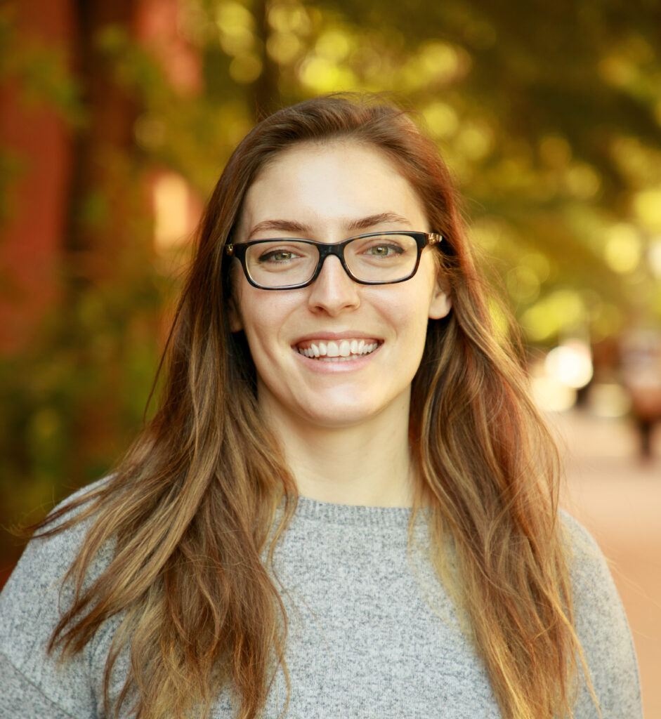 portrait of a woman outdoors wearing a gray sweater and glasses