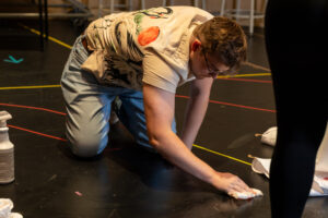 a man mops up fake blood off the rehearsal stage