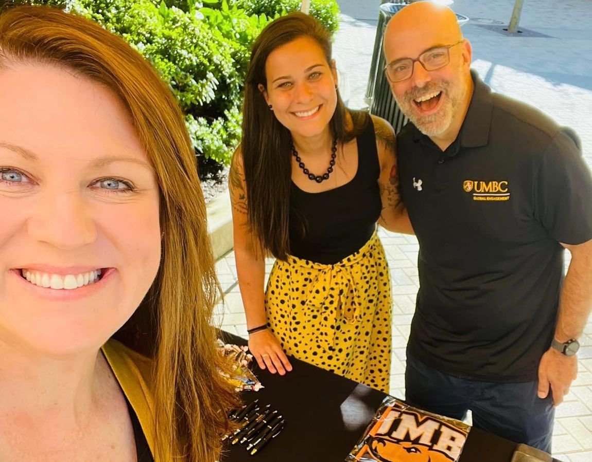 three people dressed in black and gold smile at the camera