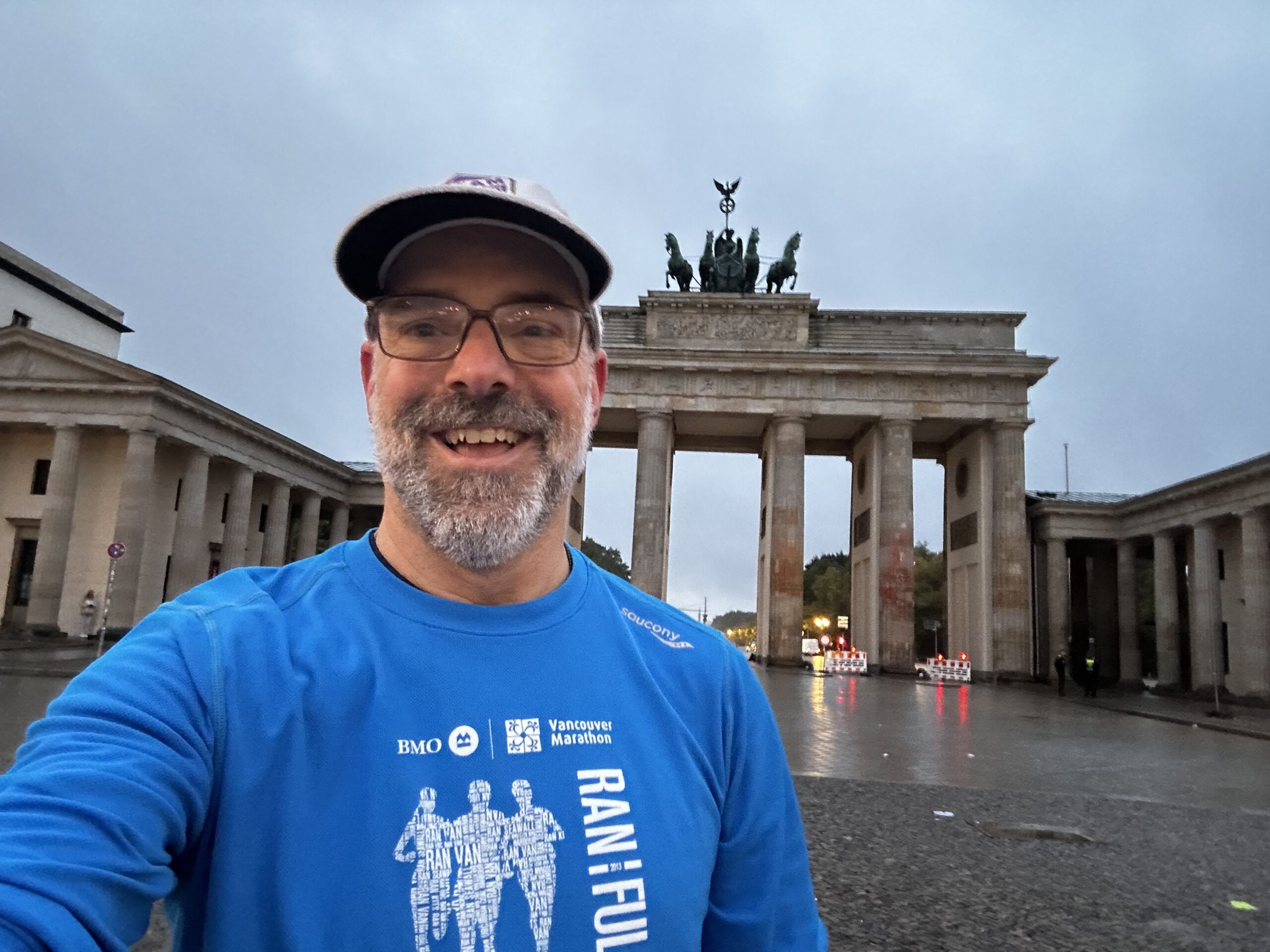 a man in running gear stands in front of the brandenburg gate in Berlin Germany