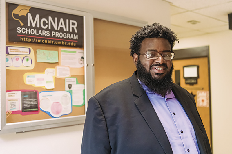 Michael Hunt standing in front of a McNair Scholars bulletin board
