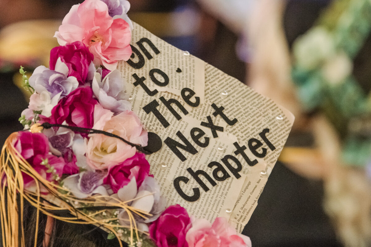 Close up shot of a decorated graduation cap that reads "on to the next chapter"