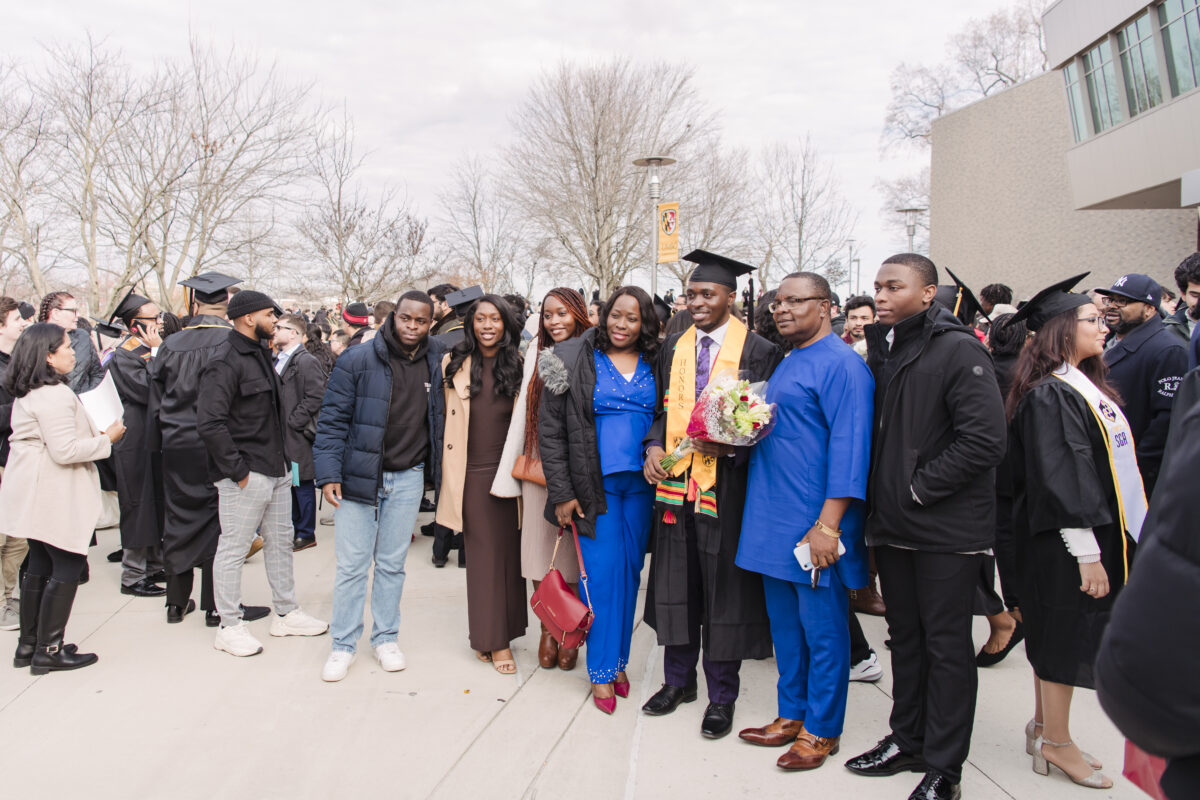 a large group of family members and supporters stand outside wit a graduate 
