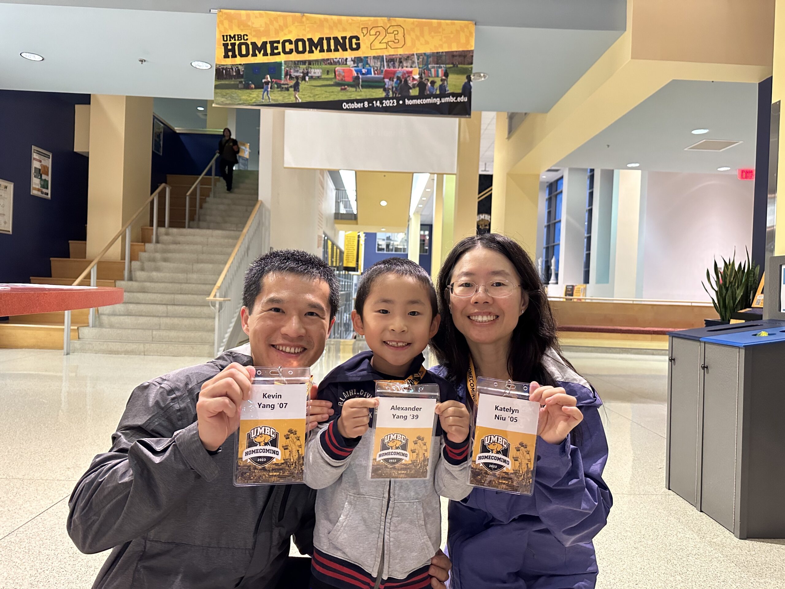 Kevin Yang '07, Katelyn Niu '05, and their son holding up their Homecoming 2023 nametags.