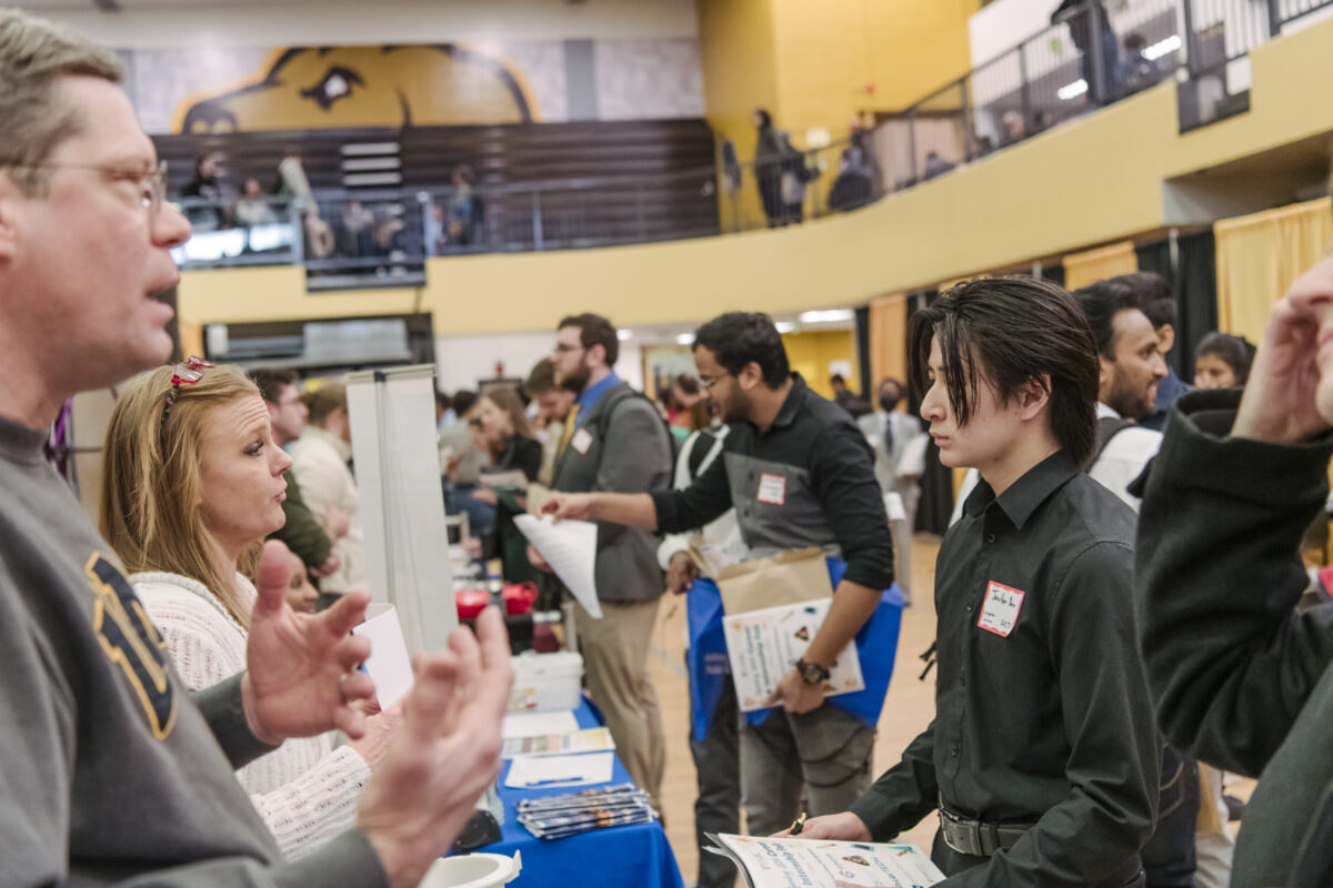 Students at a career fair talk with employers
