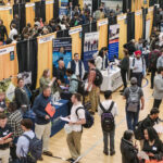A gym filled with students and booths for a career fair