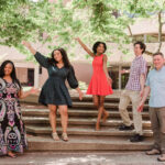 Five Fulbright college students stand outside on concrete steps with their arms outstretched