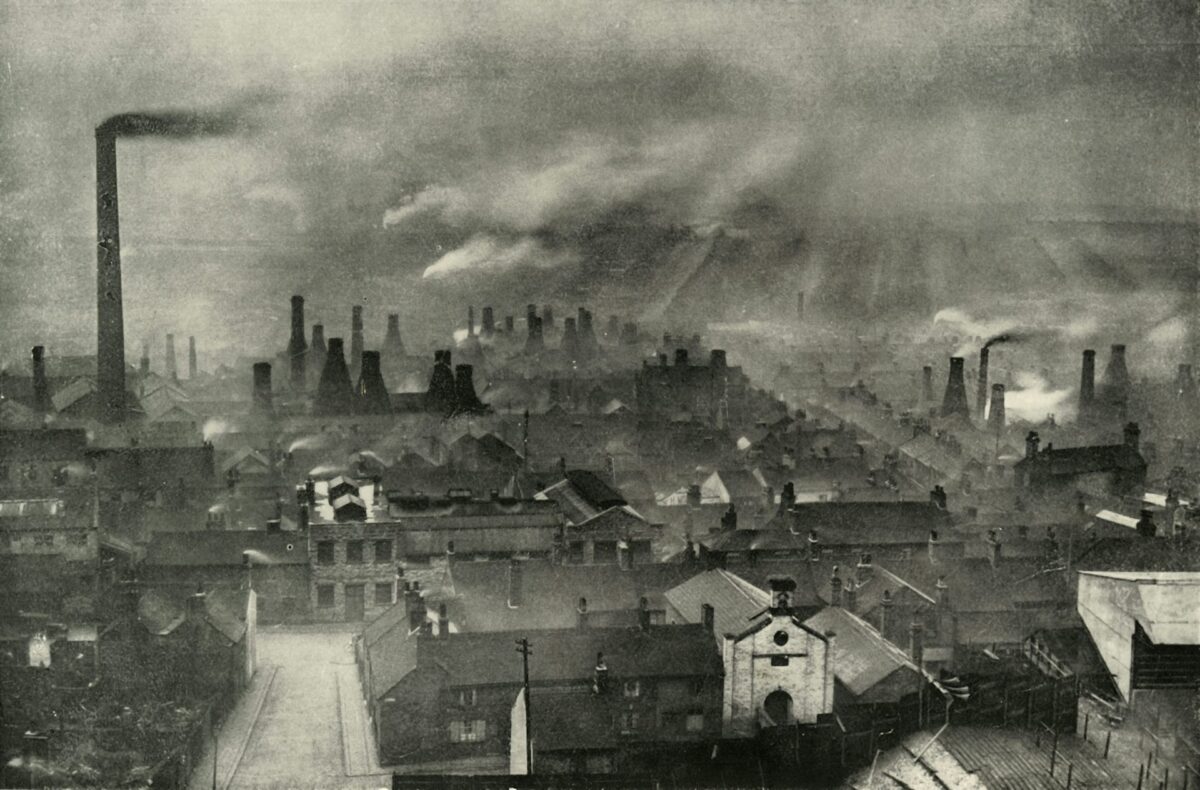 A black and white photograph of city roof tops filled with smokestacks. Anthropocene geography environmental systems