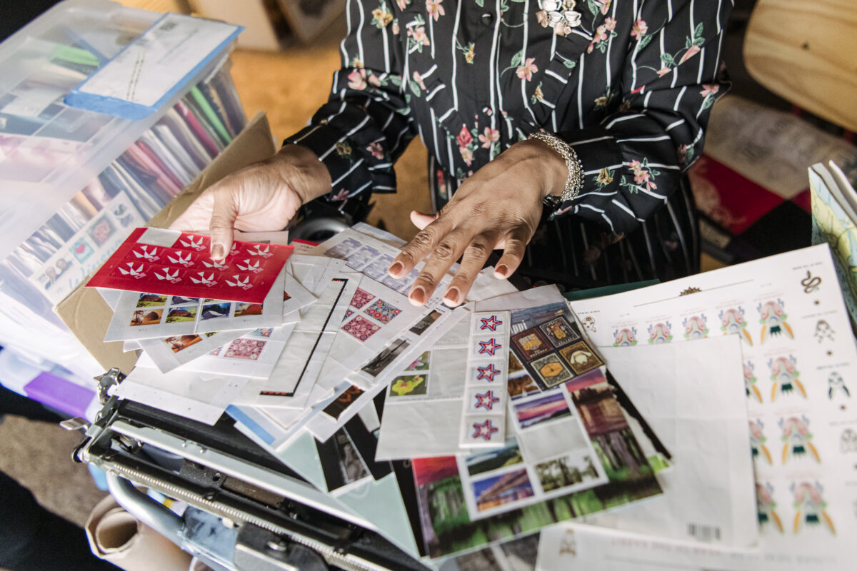 A woman sorts through many postage stamps for her pen pal hobby