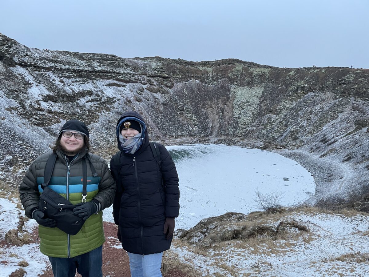 Maddy and another UMBC Humanities Scholar bundled in warm clothes stand in front of a frozen cirque with steep rock walls on all sides.