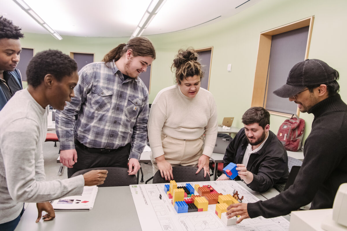 A group of college students move LEGO blocks on top of a city map.