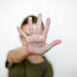 A person holding up their hand in front of their face