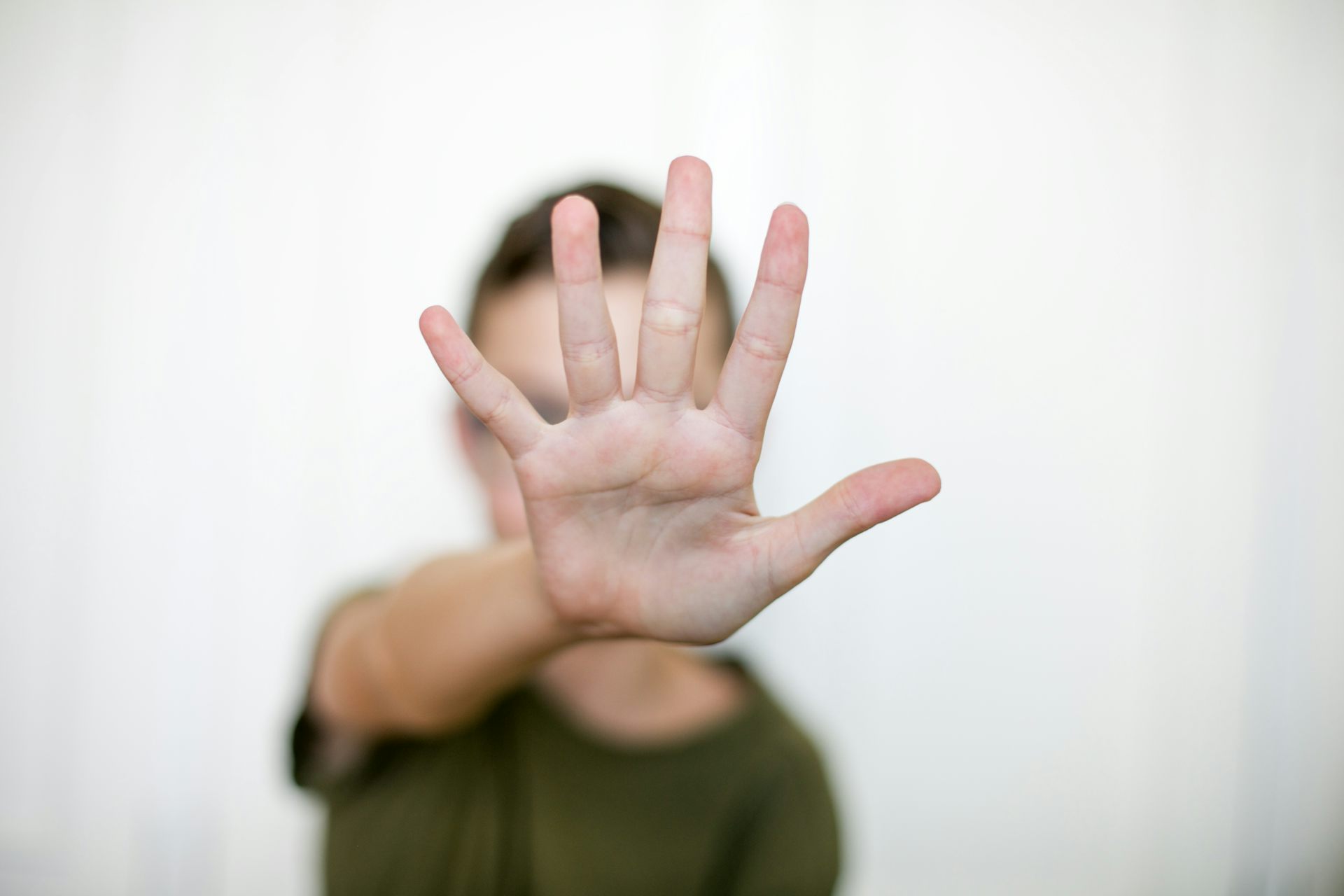 A person holding up their hand in front of their face