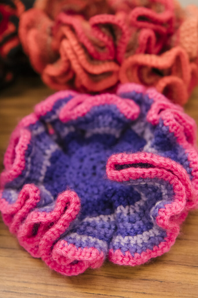 pink, purple, and orange curvy crochet creations on a wooden table