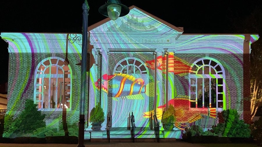 A building with a colonial style façade is covered with an illuminated projection.
