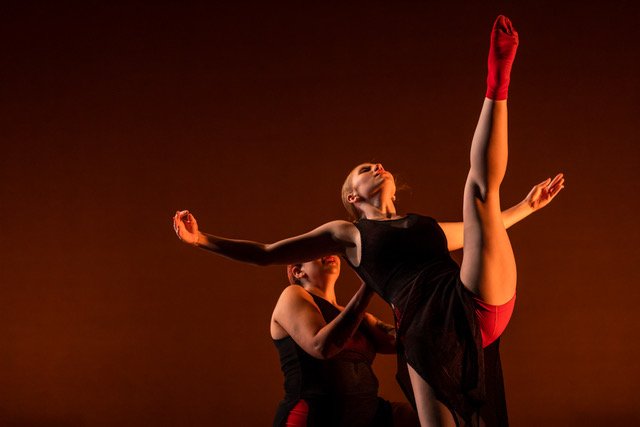 In a reddish-brown glow, two dancers perform
