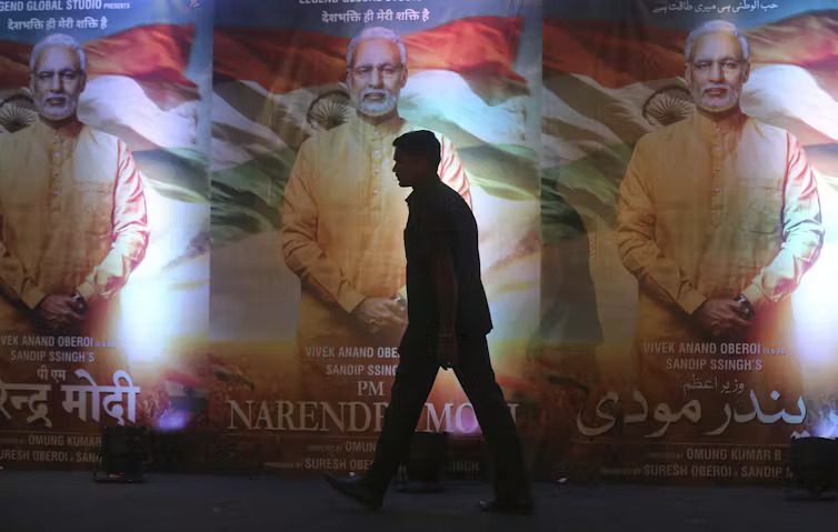 A man walks past posters of the film ‘PM Narendra Modi,’ a biopic on the Indian prime minister, during its launch in Mumbai, India,