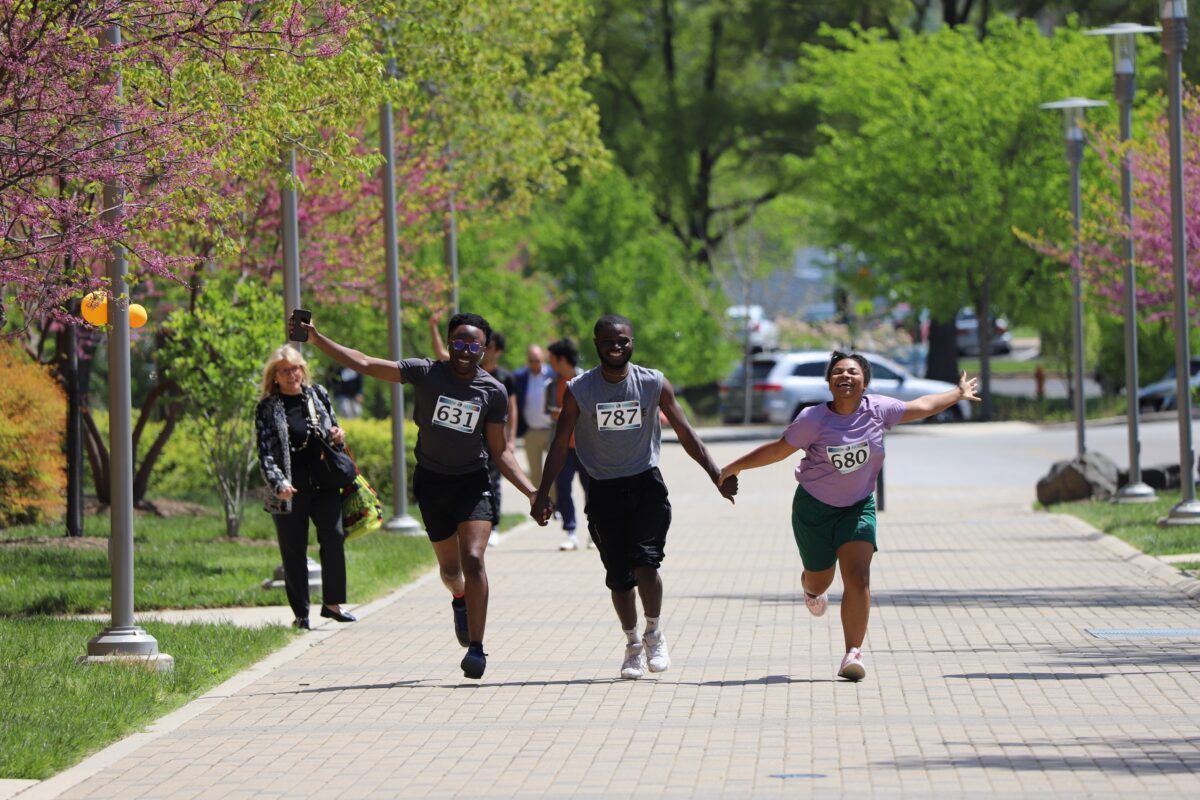 3 students hold hands running while completing UMBC's Earth Day 3K.