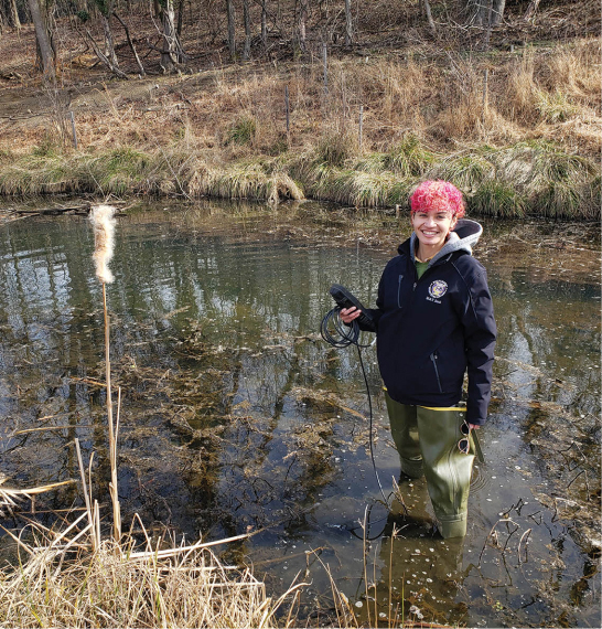 Erin Hamner collected weekly water quality  data from this stream for six months, using the battery-powered digital probe she’s holding. (Image by Sarah L. Hansen, M.S. ’15)