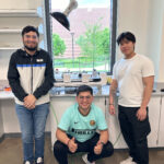 Three male students pose in a lab.