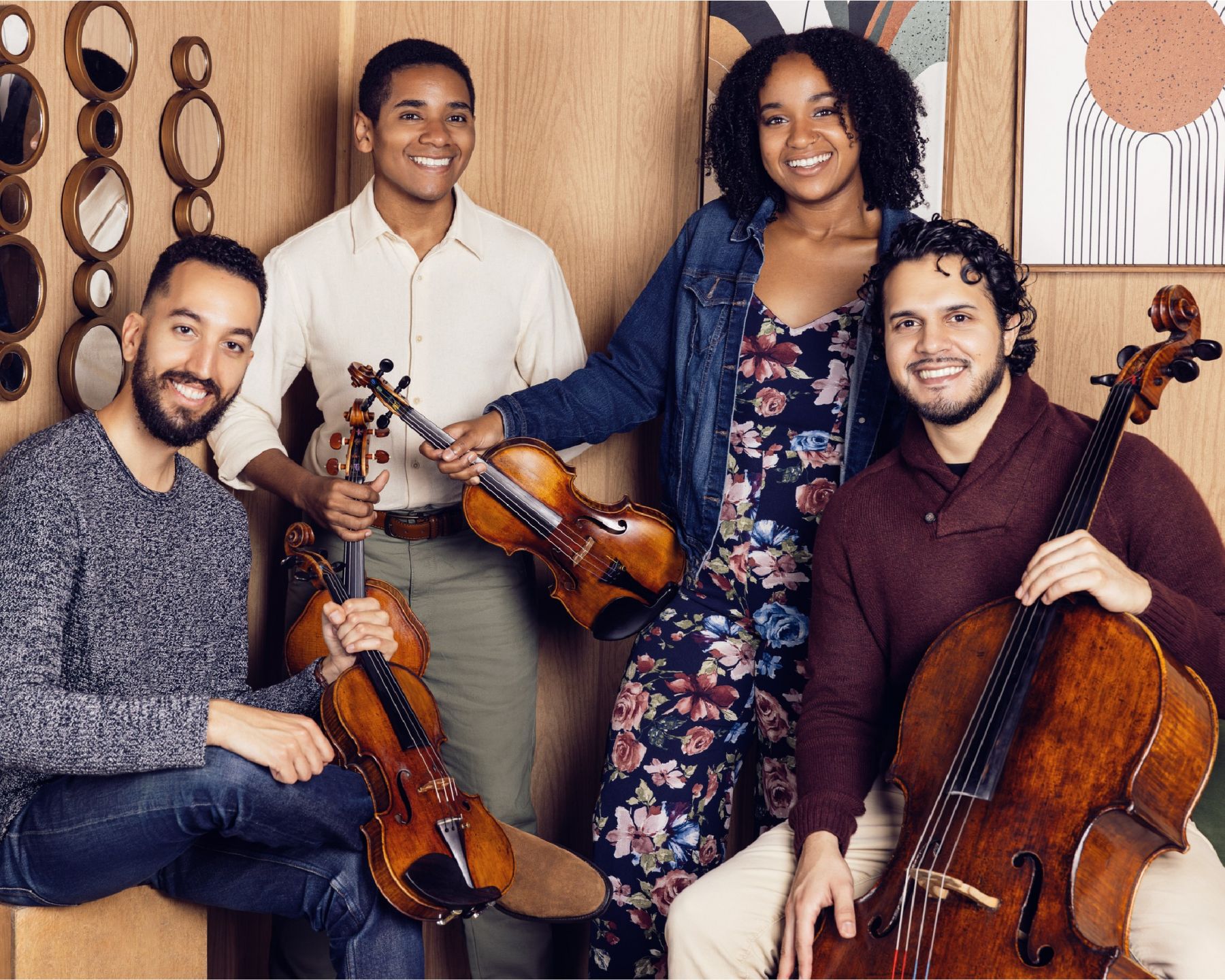 A group of four musicians pose with their string instruments.