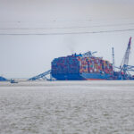 Cargo shipped in water with remains of the Francis Scott Key Bridge of top of the cargo ship