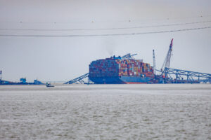 Cargo shipped in water with remains of the Francis Scott Key Bridge of top of the cargo ship