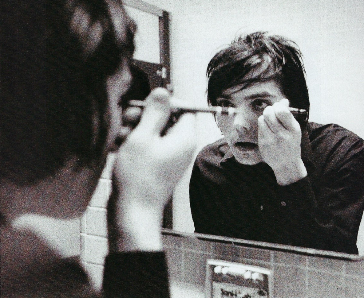 Singer, Gerard Way looking into a mirror putting on eyeliner.