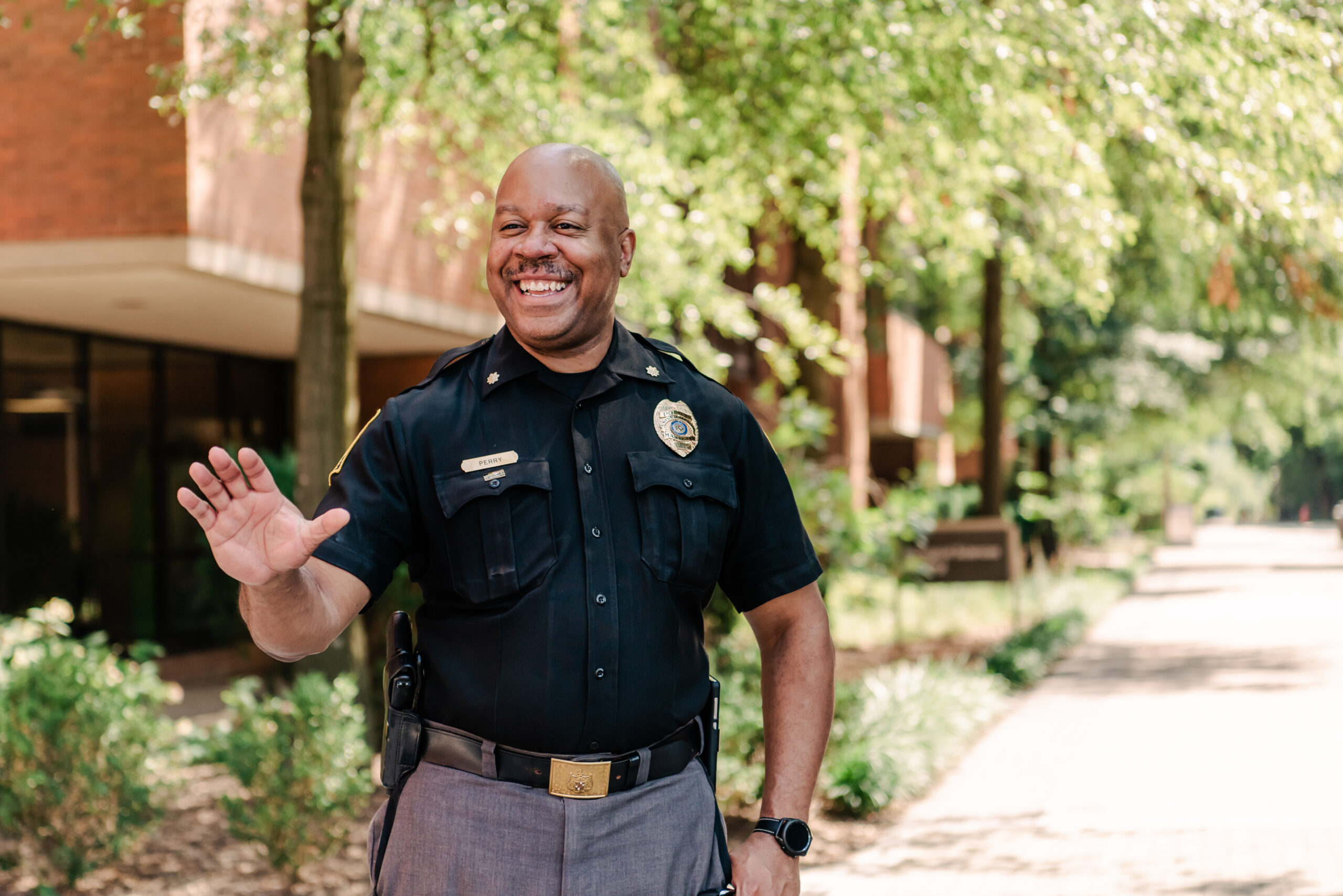 UMBC Police Chief Bruce Perry Jr. ‘97 smiling and waving to students on Academic Row.